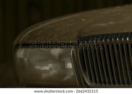 This is an image featuring a closeup view of a dirty car hood, along with the accompanying headlight, showcasing typical signs of weathering and use