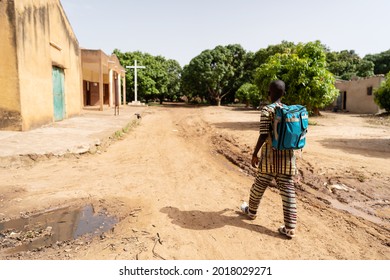 In This Image, A Lonely Well Dressed Black Boy With Blue Backpack On The Way To Sunday School Or Mass In A Deserted Christian Village In Africa