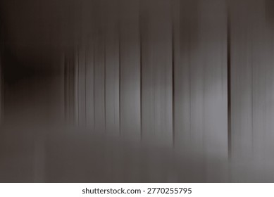 This image is a minimalist, abstract study in motion and geometry. It features a series of vertical, rhythmic lines in varying shades of charcoal, slate, and muted taupe. The composition utilizes a heavy motion blur—likely achieved through a slow shutter speed or intentional camera movement—creating a sense of ethereal transition. The foreground and left side of the frame fade into a soft, out-of-focus haze, suggesting a corridor or a series of architectural columns seen in passing. The mood is somber, introspective, and cinematic. It evokes a feeling of 
