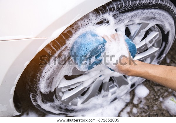 This image is a picture of\
wiping the car with a blue microfiber cloth by hands.Car wash\
concept.