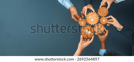 This image portrays a vibrant teamwork scenario where diverse hands hold wooden gears adorned with icons, representing collaboration and innovative business strategies. Amity