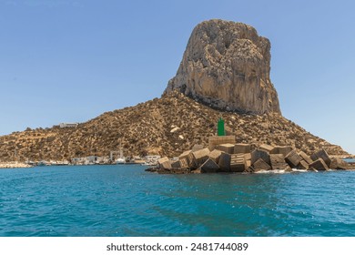 This image presents a breathtaking view of the Penon de Ifach, a massive limestone outcrop that towers over the coastal town of Calpe in Spain. 