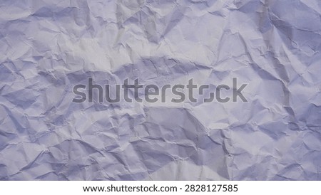 This image provides an intimate look at the texture of crumpled paper. The lighting is carefully arranged to highlight the intricate details of the folds and creases, casting abstract shapes through light and shadow. The subtle purple and blue tones add a layer of sophistication, making it an excellent choice for abstract backgrounds in various visual projects.