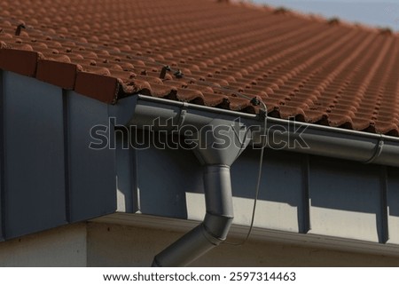 This image showcases a closeup view of a rain gutter installed on the roof of a residential house, highlighting its structural features