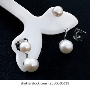 This image showcases a set of elegant pearl earrings. One pair features two pearls, while the other is a single pearl design. Both pairs feature classic white pearls and silver-toned settings.