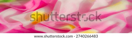 This image showcases a soft, flowing fabric in vivid pink, green, and yellow tones. The fabric appears to be translucent, with intricate folds and waves, creating a mesmerizing play of light