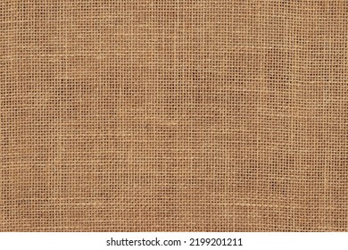 This image shows a close up view of a woven burlap surface. The tightly woven fibers are brown in color. This neutral and textured background is perfect for projects related to nature, design, agriculture, and simplicity. It could be used in projects related to crafts, packaging, rustic designs, or eco-friendly themes. The texture of the surface adds depth and visual interest. Brown burlap cloth background or sack cloth for packing. Natural linen threads texture. Sackcloth, empty space. Wrapping detail, old grainy cotton backdrop close-up.