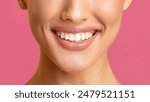 This image shows a close-up view of a womans mouth smiling with her teeth showing. The background is a solid pink color. The focus is on the womans teeth, which are white and straight.