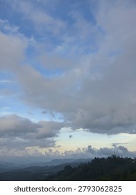 This image shows a cloudy sky over a distant mountain range.