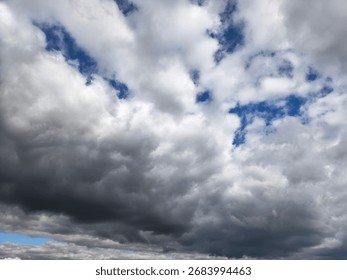 This image shows a dramatic sky filled with large stratocumulus and cumulus clouds—dark at the bottom suggesting possible rain and lighter, puffy clouds higher up.