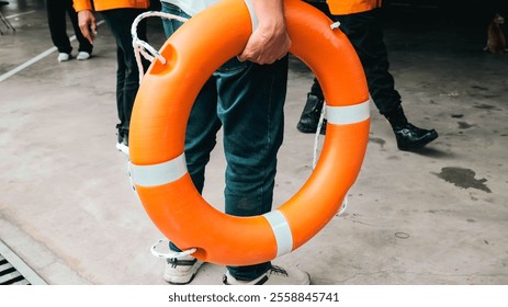 This image shows essential safety equipment including an orange life ring, life jacket, and helmets on a concrete surface, highlighting the importance of safety in water-related activities. - Powered by Shutterstock