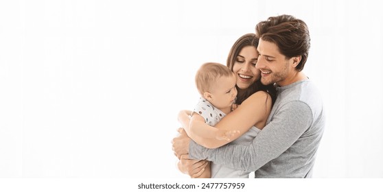 This image shows a family of three - a mother, a father, and their baby - holding each other tightly. The family is happy and smiling as they hold their little one, copy space - Powered by Shutterstock