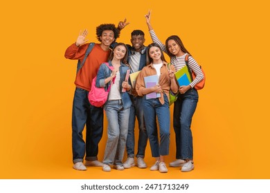 This image shows a group of diverse students smiling and posing together in front of a bright yellow background. They are all holding books and wearing backpacks - Powered by Shutterstock