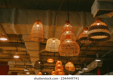 This image shows a group of lanterns hanging from the ceiling in an indoor setting. The lanterns are made of metal and have a brown finish, with black accents. They hang from the ceiling on thin chain