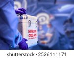 This image shows a medical professional wearing purple gloves holding a sterile transport box labeled "Human Organ for Transplant." The background appears to be a blurred surgical or medical facility.