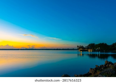 This image shows a tranquil sunset over a large body of water, l Parakrama Samudraya reservoir in Polonnaruwa, Sri Lanka. 