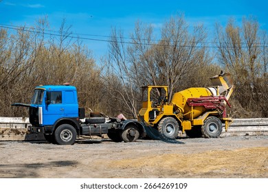 This image shows two construction vehicles parked on a dirt surface