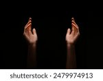 This image shows two hands reaching upward in the dark. The hands are positioned symmetrically, with their palms facing upwards.