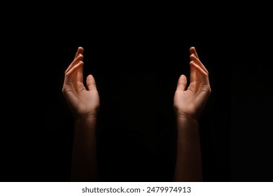 This image shows two hands reaching upward in the dark. The hands are positioned symmetrically, with their palms facing upwards. - Powered by Shutterstock