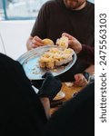 This image shows a waiter serving a tray of pinchos de tortilla, which are small pieces of Spanish omelette (tortilla espa ola) served on slices of bread. The close-up captures hands reaching for the