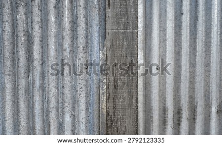 This image shows weathered silver and blue tinted corrugated tin panels with vertical ridges alongside natural wood patina boards with visible grain and knots. Screwheads and black smudges appear on one of the metal panels in even natural light.
