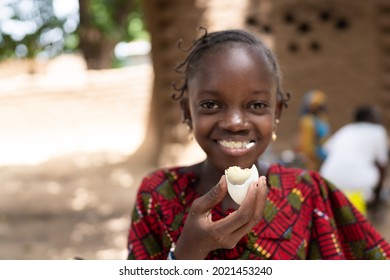 In this image, a smart black African girl is eating a boiled egg with great delight