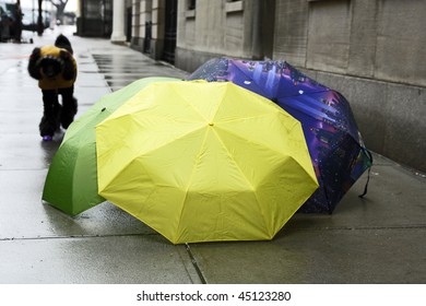 This is an image of umbrellas resting on the sidewalk in the rain.