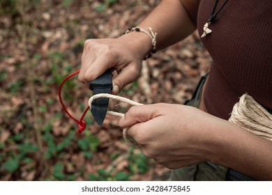 In this inspiring closeup image, a brave young adventurer stands amidst the forest, confronting a challenge with determination. With her survival knife in hand, she skillfully cuts through a rope,  - Powered by Shutterstock