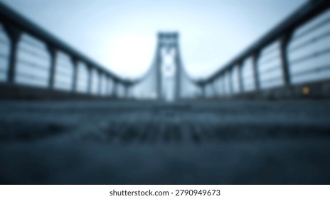This intentionally blurred, low angle photographic perspective captures the imposing structure of a suspension bridge, highlighting its central tower and the receding lines of its railings against a