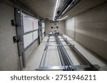 This is an interior view of an elevator shaft with the mechanical parts and wiring essential for the renovation of a freight elevator. Regular repair, servicing, and maintenance of the elevator.