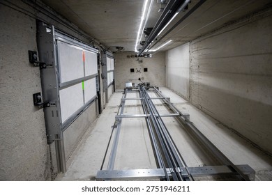 This is an interior view of an elevator shaft with the mechanical parts and wiring essential for the renovation of a freight elevator. Regular repair, servicing, and maintenance of the elevator.