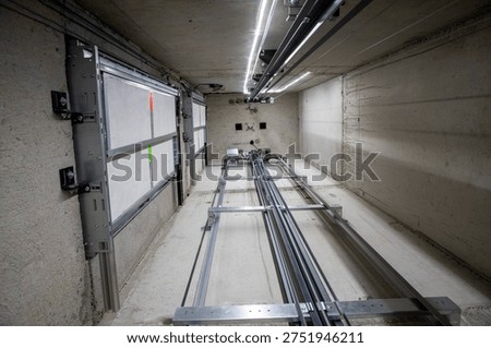 This is an interior view of an elevator shaft with the mechanical parts and wiring essential for the renovation of a freight elevator. Regular repair, servicing, and maintenance of the elevator.
