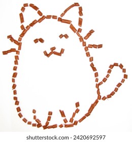 This inventive food art piece features caramel candies meticulously placed on a white surface, creating the likeness of the popular comic strip character Pusheen the Cat, recognized for its chubby