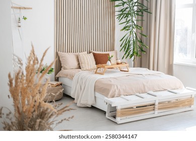 This inviting bedroom features a comfortable bed with neutral bedding and greenery.