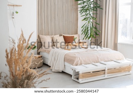 This inviting bedroom features a comfortable bed with neutral bedding and greenery.