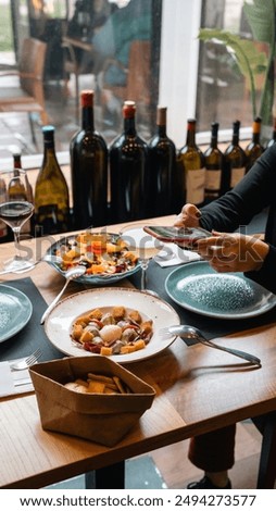 This inviting image showcases an elegant dining experience with a focus on gourmet food and fine wine. The table is set with plates of delicious food, including a colorful salad and a hearty main dish