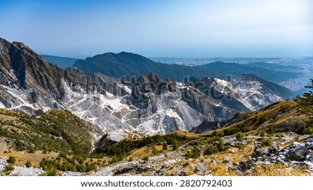 This location features the Carrara marble quarries in Italy. The area displays white marble extraction steps and surrounding mountain scenery. Mining activity is evident throughout the landscape.