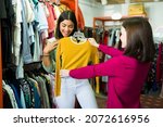 This looks good on you. Happy young woman buying second hand clothes at the clothing store