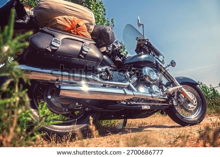 This low-angle shot captures a powerful black cruiser motorcycle, fully equipped with an array of luggage including saddlebags, a roll bag, and other travel essentials, suggesting an epic road trip 