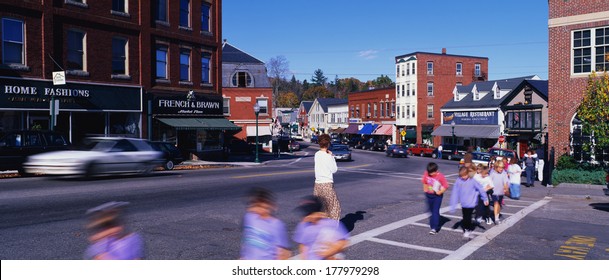 This Is Main Street Depicting Small Town America.  There Are School Children And A Teacher Crossing In The Crosswalk.