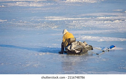 This man is ice fishing alone at the Small Boat Harbor with all the needed equipment.  Buffalo, New York, USA, January 31st, 2022
