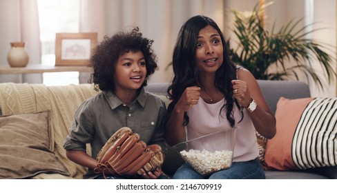 This Match Has Us At The Edge Of Our Seats. Shot Of An Adorable Little Boy Watching A Baseball Game With His Mother On Tv At Home.