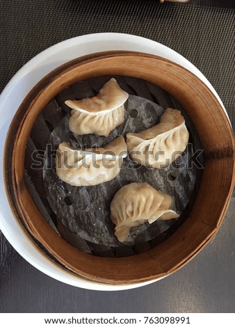 This is a menu of chinese dumling inside the wooden plate.