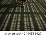In this mesmerizing image, two people walk towards the camera, bathed in the glorious sunlight emanating from the iconic Louvre Abu Dhabi building. The warm rays illuminate their path, creating a capt