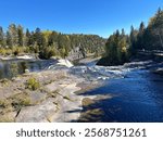 This is mid-day overlooking the main waterfall of Kakabeka Falls just before the fall colors! The trees make for a majestic backdrop against the deep blue water and sky.