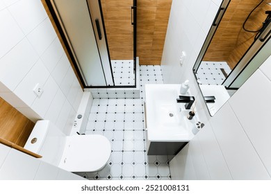 This modern bathroom features a spacious shower, sleek sink, watersaving toilet, elegant tile flooring, and warm wood accents, creating a welcoming atmosphere