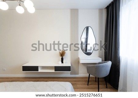 This modern bedroom features stylish furnishings, an elegant mirror, and minimalist decor, creating a bright, airy atmosphere perfect for relaxation and comfort