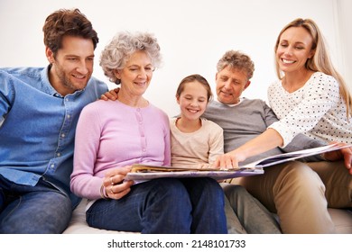 This Is My Favorite Picture Of Us. Shot Of A Happy Multi Generation Family Looking Through A Photo Album Together.