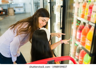 This is my favorite soft drink. Cute little girl telling her young mom to buy a big soda or juice at the supermarket 