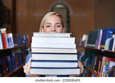 This is my study material for the semester. Portrait of a beautiful young student holding a large pile of textbooks.